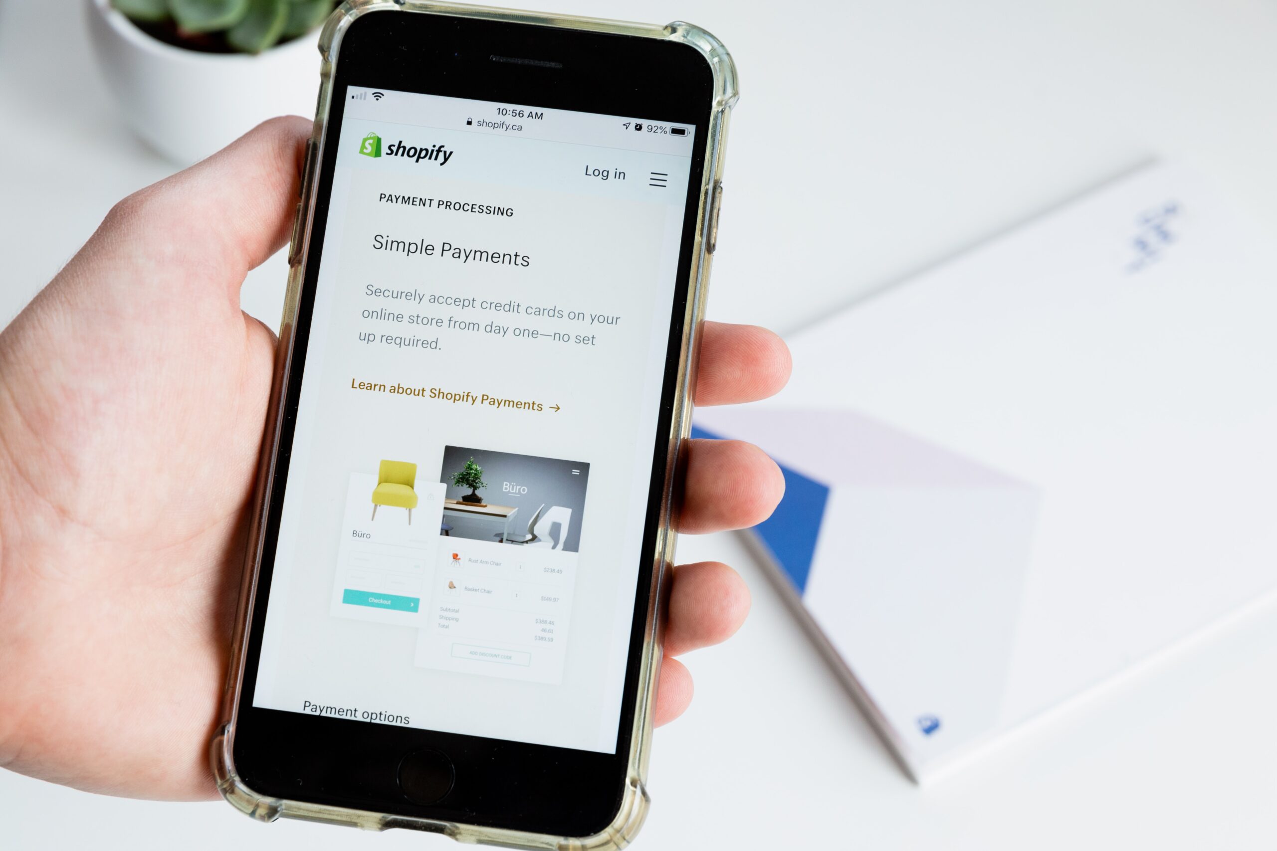 Person holding a mobile phone with the Shopify page open