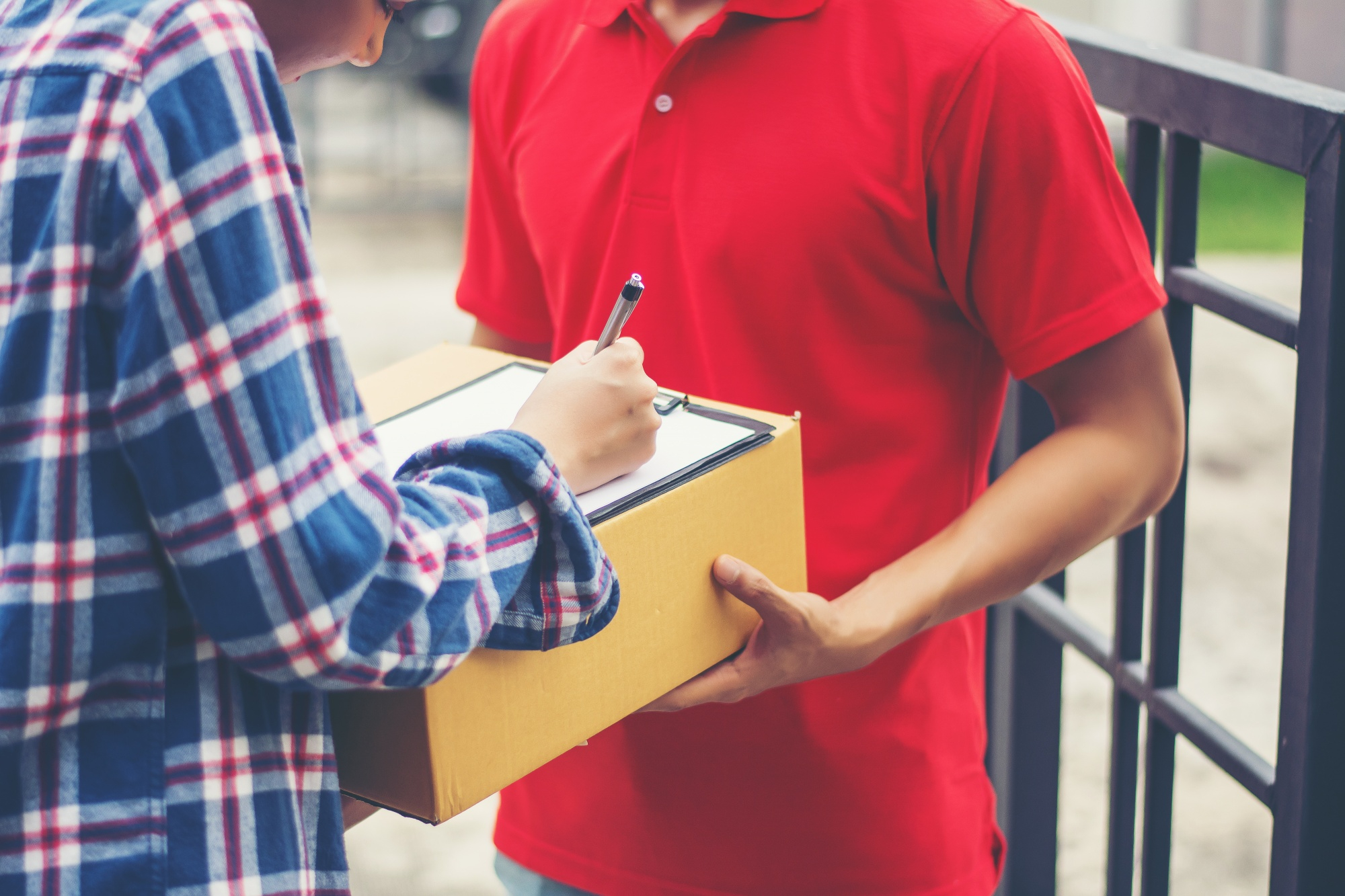 Man signing a form while receiving a package from a delivery person